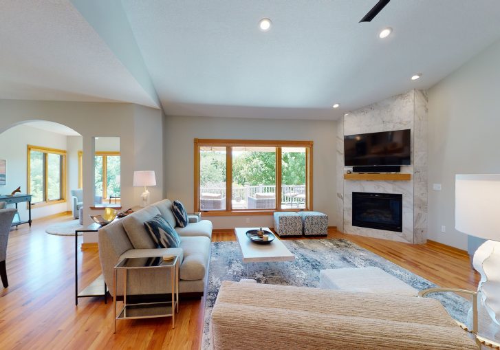 Transitional Living Room: Features a marble fireplace, wood flooring, and bronze accents throughout the space.