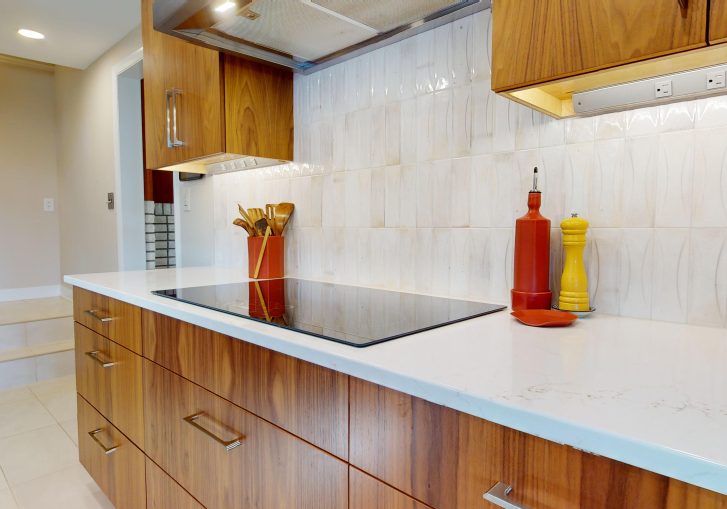 This mid-century modern kitchen remodel embraces clean lines, natural materials, and functional elegance. At its heart are our Signature Cornerstone custom grain-matched walnut cabinets in a rich natural finish, offering a seamless, sophisticated look.