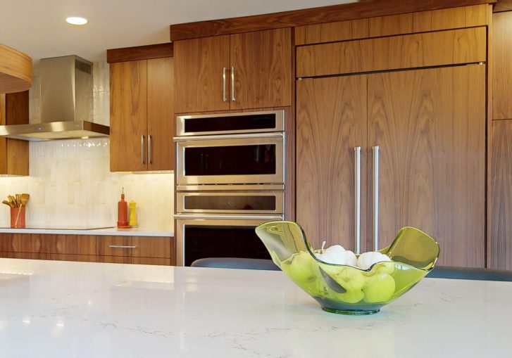 This mid-century modern kitchen remodel embraces clean lines, natural materials, and functional elegance. At its heart are our Signature Cornerstone custom grain-matched walnut cabinets in a rich natural finish, offering a seamless, sophisticated look.