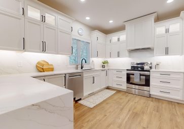 The kitchen is now a standout space, featuring Cornerstone Cabinetry in an Alabaster finish. The light cabinetry brightens the room, creating a welcoming atmosphere. A custom hood was installed, adding a striking design feature. To complete the look, the kitchen features a waterfall countertop, offering a sleek and modern touch that combines aesthetics with practicality. This kitchen is perfect for both daily use and entertaining guests.