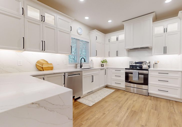 The kitchen is now a standout space, featuring Cornerstone Cabinetry in an Alabaster finish. The light cabinetry brightens the room, creating a welcoming atmosphere. A custom hood was installed, adding a striking design feature. To complete the look, the kitchen features a waterfall countertop, offering a sleek and modern touch that combines aesthetics with practicality. This kitchen is perfect for both daily use and entertaining guests.