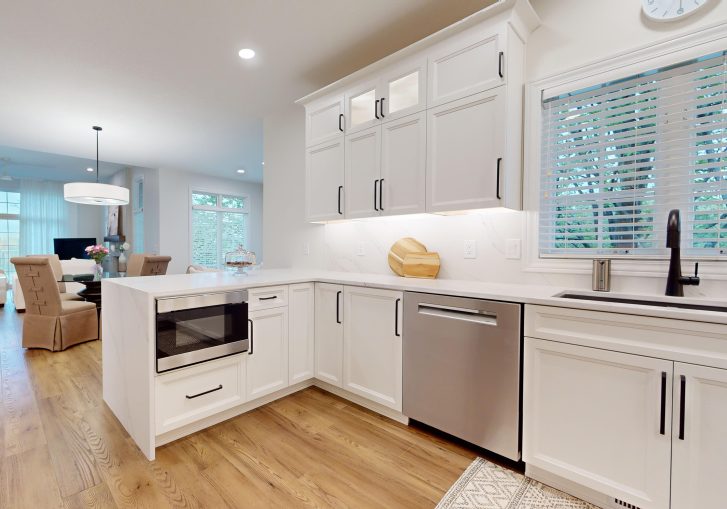 The kitchen is now a standout space, featuring Cornerstone Cabinetry in an Alabaster finish. The light cabinetry brightens the room, creating a welcoming atmosphere. A custom hood was installed, adding a striking design feature. To complete the look, the kitchen features a waterfall countertop, offering a sleek and modern touch that combines aesthetics with practicality. This kitchen is perfect for both daily use and entertaining guests.