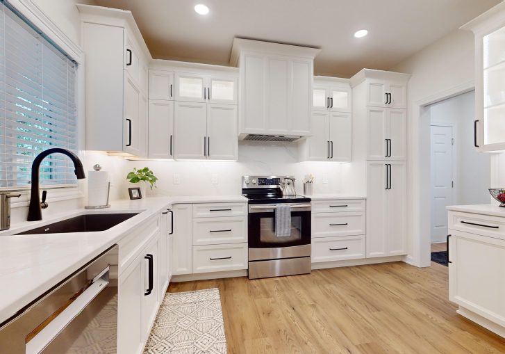 The kitchen is now a standout space, featuring Cornerstone Cabinetry in an Alabaster finish. The light cabinetry brightens the room, creating a welcoming atmosphere. A custom hood was installed, adding a striking design feature. To complete the look, the kitchen features a waterfall countertop, offering a sleek and modern touch that combines aesthetics with practicality. This kitchen is perfect for both daily use and entertaining guests.