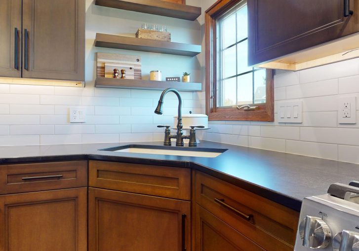 The addition of floating shelves above the coffee bar adds both practicality and personality to the space. These shelves provide extra storage for everyday items while offering the perfect spot for displaying unique pieces that reflect the homeowner's taste and style. The clean lines and minimalist design of the shelves help maintain an open, airy feel in the kitchen.