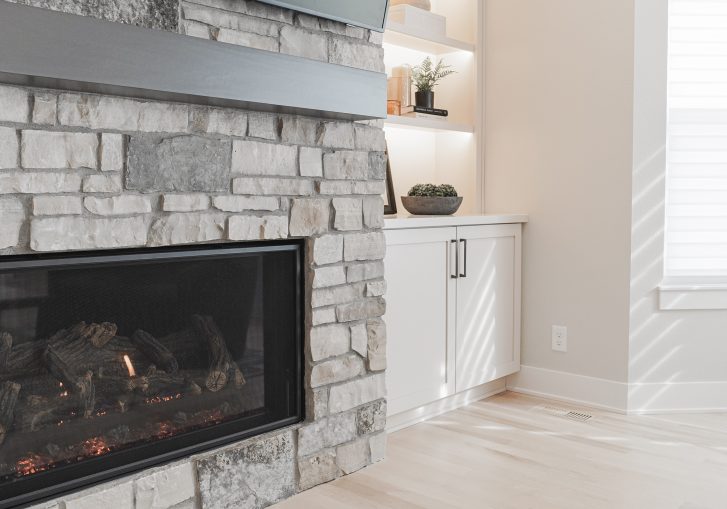 The living room remodel is a showstopper, featuring a striking stacked stone fireplace, which serves as the focal point of the space.