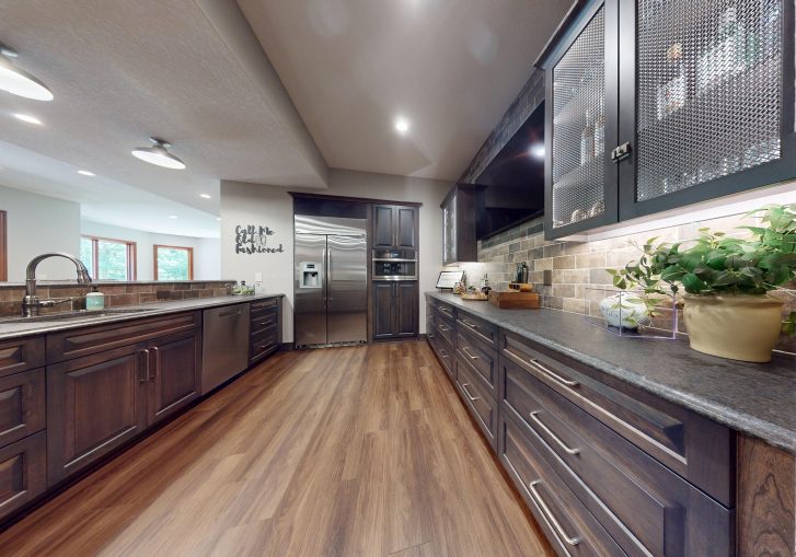 The granite countertops throughout the kitchen and bar area bring durability with high-end polish. Their natural veining and finish play beautifully against the darker tones of the cabinets and brick, adding visual balance and refinement.