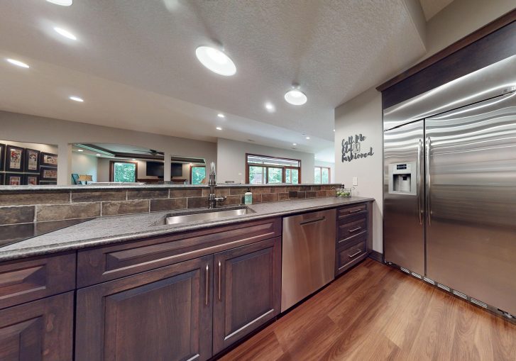 Custom Cornerstone Cabinetry cherry cabinets in a deep, warm finish add to a sense of elegance and timelessness. The natural richness of the wood brings warmth to the space, reinforcing the cozy, vintage-inspired design while providing ample storage for barware, mixers, and more.