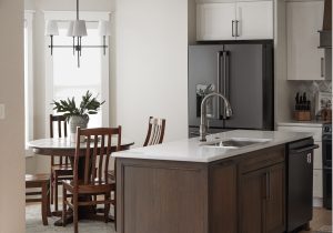A Kitchen Remodel in Des Moines with lightly painted cabinets, a dark stained island an marble countertops and tile backsplash.