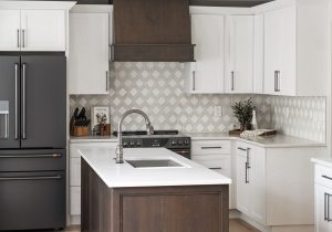 A full kitchen remodel in Des Moines with a custom wood hood, white countertops and tile backsplash.